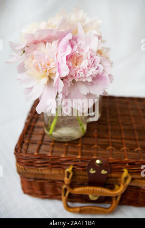 Einen sehr schönen Blumenstrauß rosa Pfingstrosen in Vase steht auf einem Holz- Koffer. Schöne Komposition. Stockfoto