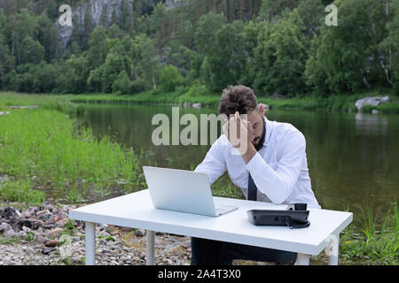 Junge Unternehmer in einem Zustand von Stress, Müdigkeit und Kopfschmerzen, er hält seine Hand auf den Kopf. Junger Mann Probleme beim Studieren Stockfoto