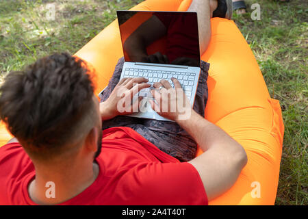 Mann bei der Arbeit auf seinem Laptop mit leeren Bildschirm. Der Mann von der Texteingabe auf seinem Computer Stockfoto