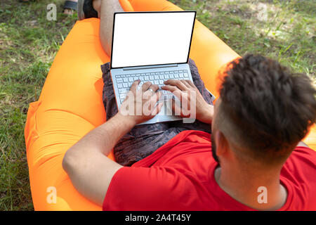 Mann bei der Arbeit auf seinem Laptop mit leeren Bildschirm. Der Mann von der Texteingabe auf seinem Computer. Platz für Text auf dem Bildschirm Stockfoto