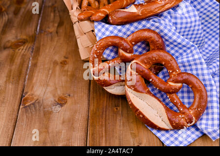 Bayerische Brezel geschmückt mit einem blauen und weißen Tuch an einem rustikalen Holzbrett - Münchner Oktoberfest. Hintergrund und freier Platz für Text. Traditionelles Gebäck für das Festival Stockfoto