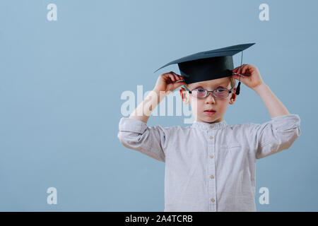 Redhead erster Sortierer Junge in Gläser zur Festsetzung seiner Student hat über blauer Hintergrund Stockfoto