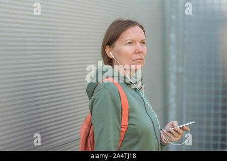 Brisk Walker weiblich Musik hören über Kopfhörer, Porträt der Frau in Sportkleidung in der städtischen Umgebung Stockfoto