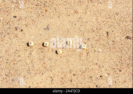 Die Buchstaben auf die hölzerne Würfel sind in das Wort Entspannung auf dem Sand gefaltet Stockfoto