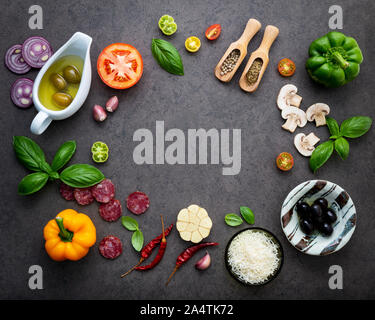 Die Zutaten für selbstgemachte Pizza auf dunklem Stein Hintergrund. Stockfoto