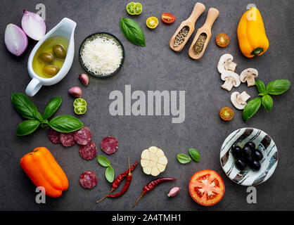 Die Zutaten für selbstgemachte Pizza auf dunklem Stein Hintergrund. Stockfoto