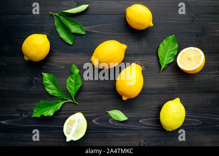 Frische Zitronen und Zitronen Blätter auf dunklem Hintergrund. Stockfoto