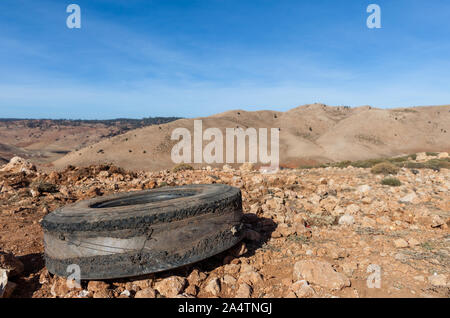 Alte durchgebrannt und verschlissene Reifen im Dreck lag und Kies neben einer Straße in Marokko. Einige Hügel sind im Hintergrund sichtbar. Stockfoto