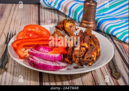 Lamm Rippen mit Gewürzen mariniert Gegrillte in einem Teller auf dem Tisch. Mit in Scheiben geschnittenen Tomaten, Paprika und Zwiebeln Stockfoto