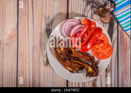 Lamm Rippen mit Gewürzen mariniert Gegrillte in einem Teller auf dem Tisch. Mit in Scheiben geschnittenen Tomaten, Paprika und Zwiebeln Stockfoto