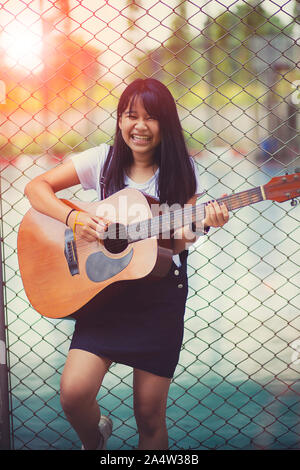 Asiatischen Teenager spielen spanische Gitarre mit Glück emotion Stockfoto