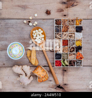 Alternative health care getrocknet verschiedene chinesische Kräuter in Holzkiste und getrocknete Quitte, Ingwer und Lotus Samen in Löffel aus Holz mit chinesischen Tee Tasse auf alten Stockfoto