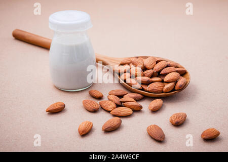 Hausgemachte Mandelmilch in vintage Flasche mit Mandel in den hölzernen Löffel setup auf braunen Hintergrund. Stockfoto