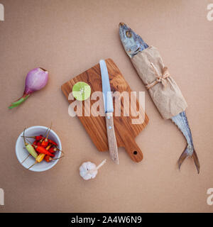 Vorbereiten kochen traditionelle Thai Food gesalzener Fisch Salat mit Chili, Zwiebel, Limette, Koriander, Knoblauch und Zitronengras auf braunem Papier Board erhalten. Stockfoto