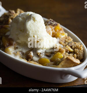 Nahaufnahme von Pfirsich und Pecan Schuster mit einem Schmelzpunkt Kugel Vanilleeis. Stockfoto