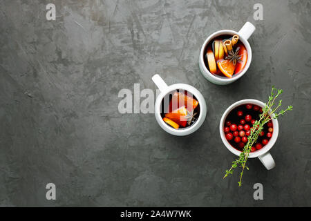 Weihnachten heißer Glühwein trinken in ein Becher mit Orange, Zitrone, Apfel, Zimtstangen und Sterne Anis auf Dunkelgrau konkreten Hintergrund der Ansicht von oben Stockfoto