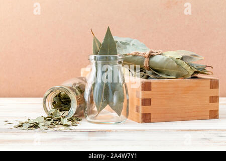 Flasche getrocknete Lorbeerblätter und Holzbox mit selektiven Fokus auf Holz- Hintergrund. Stockfoto