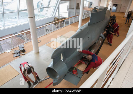 Bremerhaven, Deutschland. 16 Okt, 2019. Arbeitnehmer push ein Miniatur-U-Boot der "Deal" Art von Weltkrieg II aus seinem alten Platz im Deutschen Schiffahrtsmuseum in das Fenster vorne, so dass es von dort in das Erdgeschoss gehoben werden können. Nach einer umfangreichen Rekonstruktion, Museum die Ausstellung wird ein Platz im Erdgeschoss finden. Um die 12 Meter lange und 12 Tonnen schwere U-Boot Es zu transportieren, eine grosse Fensterfront wurde entfernt. Quelle: Jörg Sarbach/dpa/Alamy leben Nachrichten Stockfoto