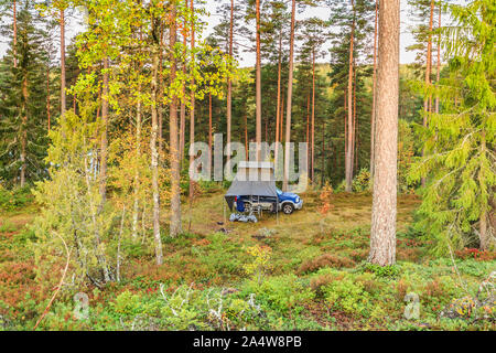 Wildes Campen in Schweden mit 4x4 Gelände wagen und Dachzelt in einem natürlichen Wald am Fuße eines Hügels, mit schönen Herbstfarben im warmen Licht Stockfoto