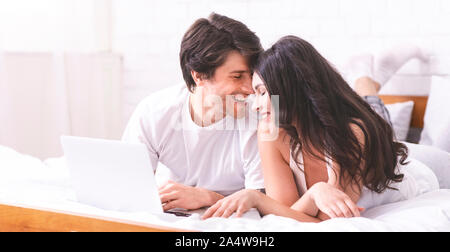 Junger Mann und Frau Surfen auf dem Laptop im Bett Stockfoto
