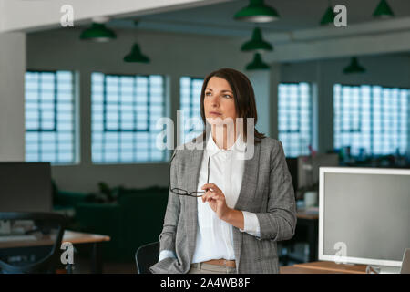 Geschäftsfrau stehend in einem Büro, tief in Gedanken Stockfoto
