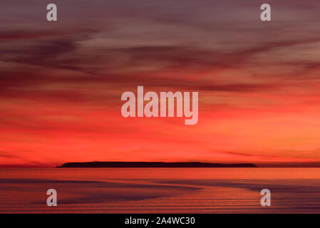 Eine dramatische Roter Himmel am Ende der Mitte Sommer Sonnenuntergang über Lundy Island in den Atlantischen Ozean von Westward Ho gesehen! In North Devon, England. Stockfoto