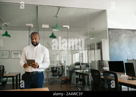 Afrikanische amerikanische Geschäftsmann auf einem Tablet in seinem Büro Stockfoto