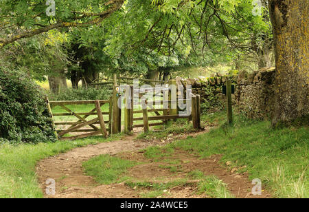 Englisch ländliche Landschaft in den Cotswold Hills mit Track führt zu einer Wand und Tor Stockfoto