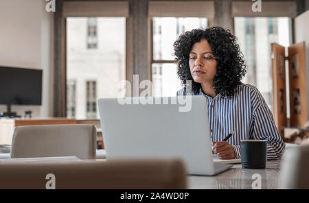 Junge weibliche Unternehmer auf Ihrem Laptop zu Hause arbeiten Stockfoto
