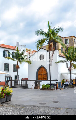 Funchal, Madeira, Portugal - Sep 10, 2019: Straßen in Madeiras Hauptstadt mit typischen Gebäuden aus der Kolonialzeit. Die Menschen trinken und essen auf der Terrasse im Freien. Palmen. Historische Altstadt. Stockfoto