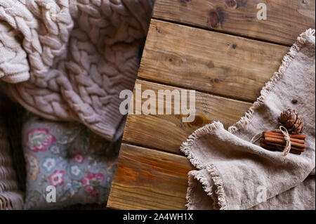 Gemütliche gestrickte Pullover auf einen Sessel und einen Holztisch mit. Herbst Winter Konzept. Stockfoto