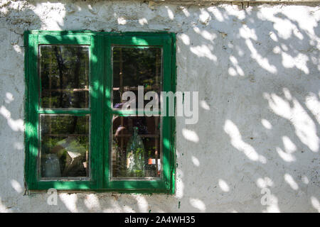 Alten rostigen grünes Fenster mit Flaschen hinter dem Glas, aussen. Beschädigte grüne Farbe Textur auf ein Fenster Stockfoto