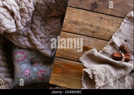 Gemütliche gestrickte Pullover auf einen Sessel und einen Holztisch mit. Herbst Winter Konzept. Stockfoto