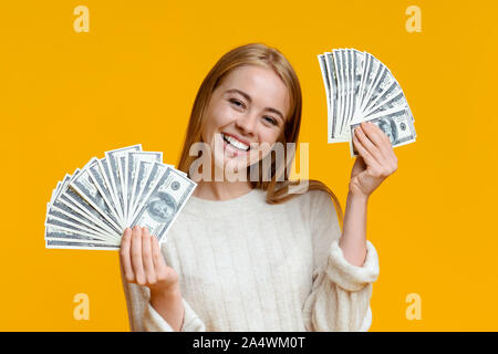 Happy tausendjährigen Mädchen, dass viele Dollar auf dem orangen Hintergrund Stockfoto