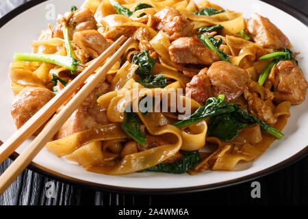 Straße Thai Essen Nudeln mit Huhn, Chinesischer Brokkoli und Ei close-up auf einem Teller auf den Tisch. Horizontale Stockfoto
