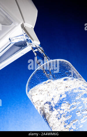 Wasser gießen aus Kanne in Klarglas Stockfoto