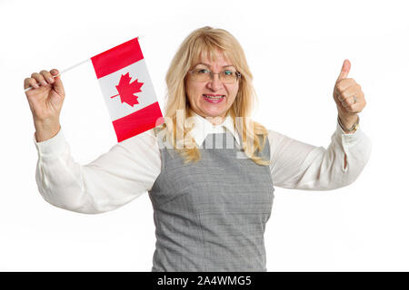 Gerne reife Frau mit Flagge von Kanada mit Daumen nach oben, nach vorne in die Kamera schaut, auf weißem Hintergrund. Kanadische Frauen. Reisen und Lernen Stockfoto