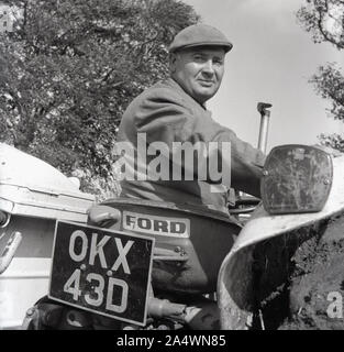 1967, historisch, ein Farmer mit Stoffmütze, sitzt auf einem Ford-Traktor beim Young Farmers Pflügen Wettbewerb in Long Crendon, Bucks, England, Großbritannien. Stockfoto