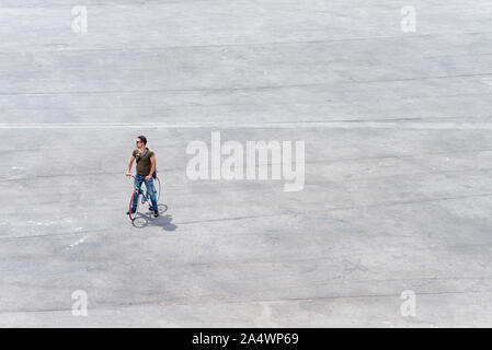 Junger Mann, der mit seinem Fahrrad auf ein Quadrat (Copyspace) Stockfoto