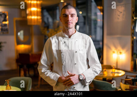 Jung brutal gutaussehend Koch Leiter in modernem Luxus Restaurant Interior posieren. Stockfoto