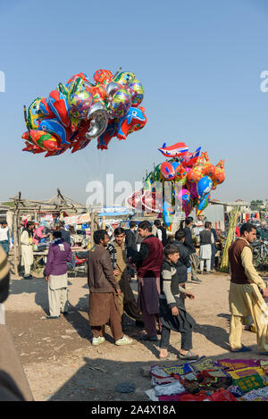 PESHAWAR in Pakistan, 13 Dezember, 2015: Junge verkauft seine Folie Luftballons in Markt am Sonntag in Hayatabad Stadt in Peshawar in Pakistan Stockfoto