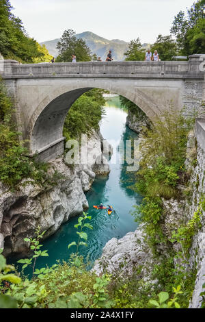 Historische Napoleon-Brücke über den Fluss Soca bei Kobarid, Slowenien. Die Leute fahren mit dem Kajak im türkisfarbenen Fluss. Stockfoto