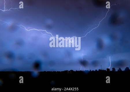 Gewitter erzeugt horizontale und vertikale Blitzeinschläge mit Niederschlag während der stürmischen Wetter. Regentropfen auf der Linse. Stockfoto