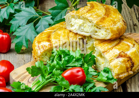 Georgische khachapuri Torten mit Käse auf Holzplatte, Käse, Paprika, Tomaten, Pilze, Kräuter, Zwiebel und Schüsseln mit Gewürzen in der Nähe auf dem Tisch. Stockfoto