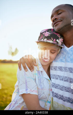 Mixed Race Paar millennials in einem Gras Feld kuscheln und s Stockfoto