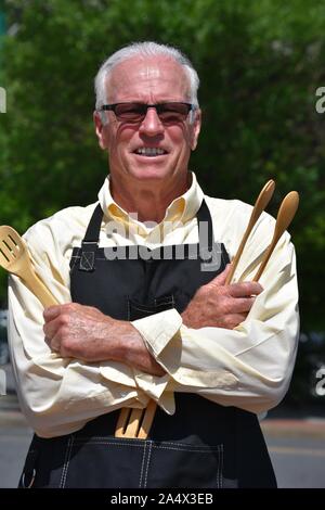 Gerne männliche Cook tragen Schürze mit Küchengeräte Stockfoto