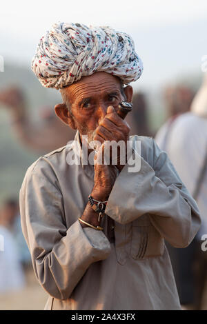 Rajasthani Mann Rauchen ein Chillum (Rohr) von Haschisch in Pushkar Camel Fair, Rajasthan, Indien Stockfoto