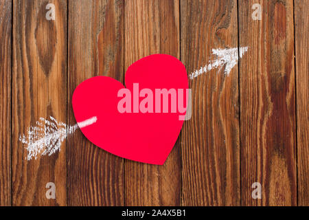 Valentine Karte zum Valentinstag rot Herz aus Papier wurde mit einem Pfeil in Kreide auf Holzbrettern gezeichnet löchrig Stockfoto