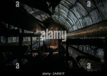 Runde Beton U-Bahn Tunnel der Heizungsleitung System mit rostigen Rohren. Stockfoto