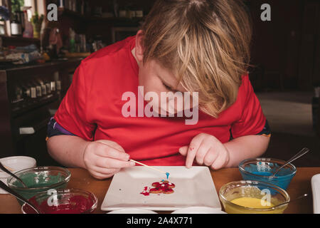 Junge dekorieren Lebkuchen mit Zuckerguss und Zahn pick Stockfoto